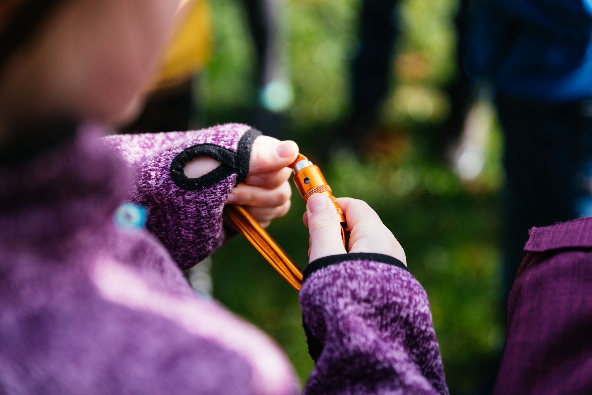 Kind mit Karabiner zur Vorbereitung für Kletterkurs in der Schule